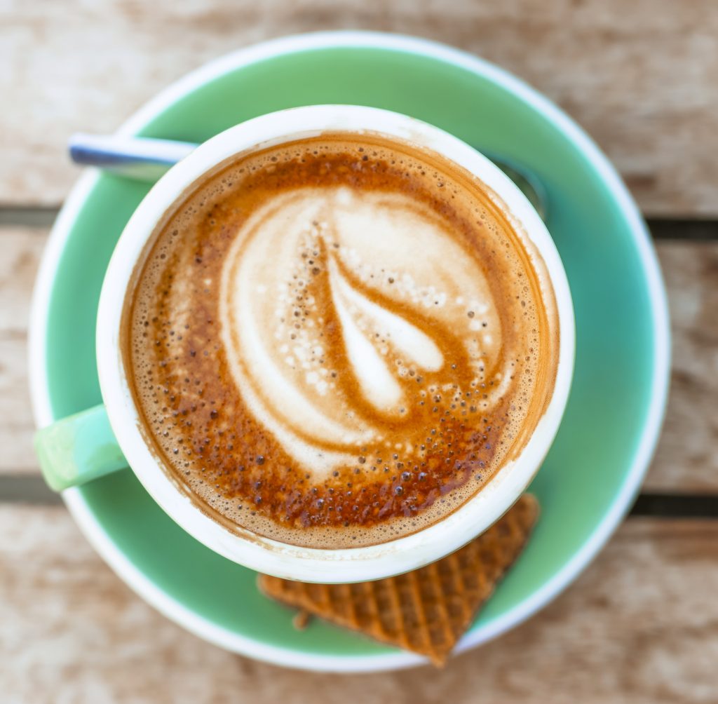 Cup of coffee with chocolate and wafer on a wooden table. A perfect setting to discuss how support from 64G Ltd can help your business grow.